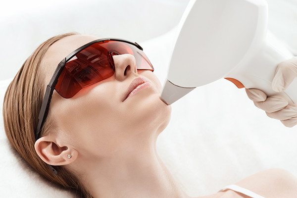 Close-up view of young woman receiving laser skin care on face