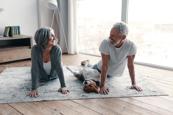 Older couple doing yoga on mat with their dog